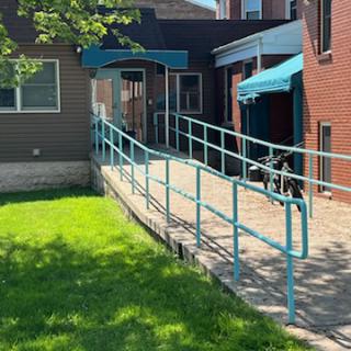 A wheelchair-accessible ramp leading to the entrance of a building, surrounded by green grass.