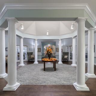 Elegant interior design featuring pillars and a central table with floral decor.