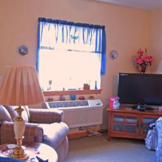 A cozy living room with a TV, lamp, and window with blue curtains.