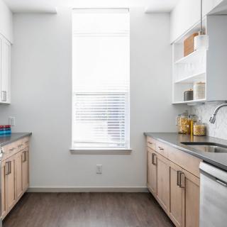 A bright and modern kitchen with light wood cabinets and a large window.
