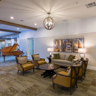 A well-furnished living room with elegant seating and a piano in the background.