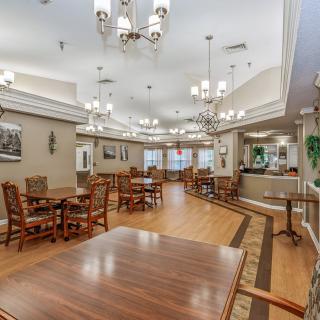 A spacious and elegantly decorated dining area with wooden floors and chandeliers.
