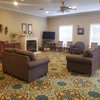 A cozy living room with sofas, armchairs, a television, and a fireplace.