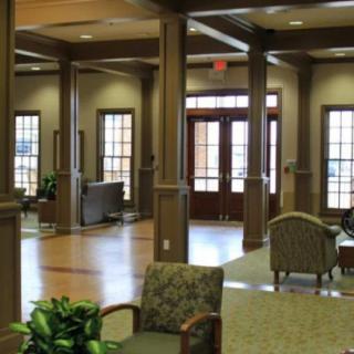 A spacious lobby area featuring comfortable seating, plants, and wooden columns.
