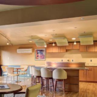 A modern kitchen with wooden cabinets and bar stools in a spacious open layout.