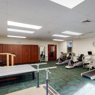 A bright and spacious rehabilitation gym equipped with various exercise machines and physical therapy tools.