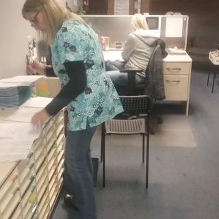 Two women working in an office, organizing files and paperwork.