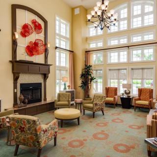 A spacious and well-lit living room featuring a fireplace, elegant chandelier, and comfortable seating with vibrant decor.
