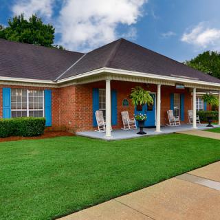 A charming brick house with a welcoming front porch and well-maintained lawn.