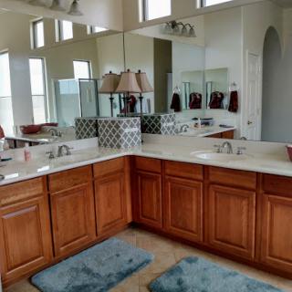 A spacious and well-lit bathroom featuring dual vanities, wooden cabinetry, and decorative mirrors.