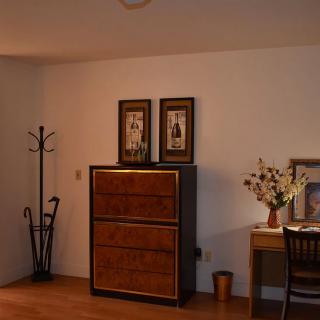 A cozy room with a wooden cabinet, decorated desk, and coat rack.