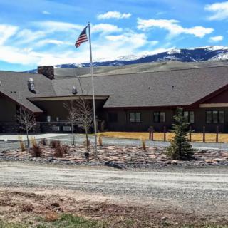A building with an American flag in front, set against a mountainous landscape.