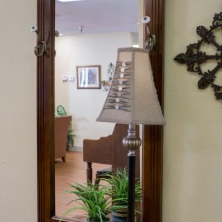 A mirror reflecting a cozy living space with a lamp, plants, and furniture.