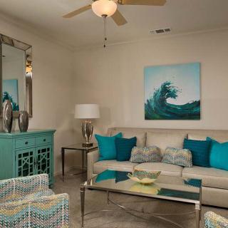 A modern living room with a beach-themed decor featuring turquoise accents and neutral tones.