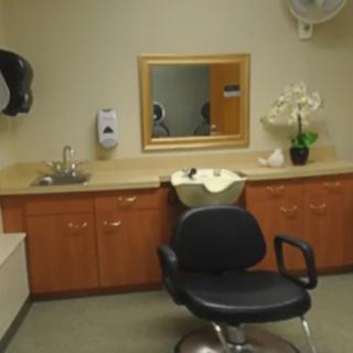 A hair salon setup with a chair, sink, and mirror.