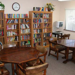 A cozy library room with bookshelves, tables, and chairs.