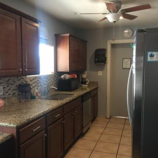 A modern kitchen with dark wooden cabinets, a granite countertop, and stainless steel appliances.