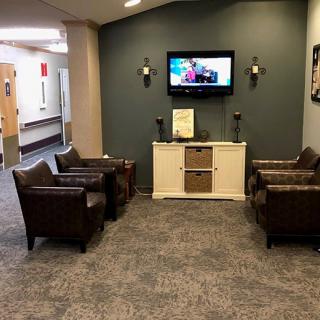A cozy waiting room with comfortable chairs and a television mounted on the wall.