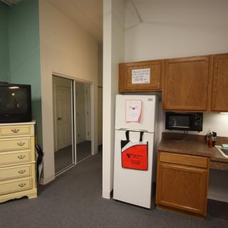 A compact kitchen area with a refrigerator, microwave, and adjacent television.