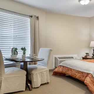 Cozy bedroom interior with a small dining area and large window.