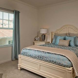 A cozy bedroom with a neatly made bed, soft lighting, and elegant furnishings.