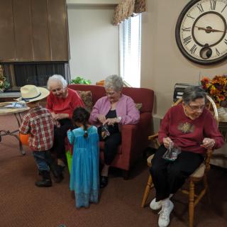Children in costumes visiting seniors in a community setting.