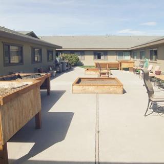 A spacious outdoor courtyard with tables, chairs, and benches on a sunny day.