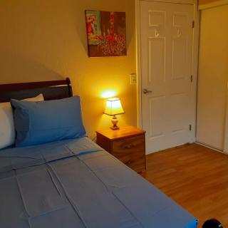 A cozy bedroom with a neatly made bed, nightstand, and soft lamp lighting.
