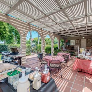 An inviting outdoor patio setup with tables, chairs, and a BBQ grill under a pergola.