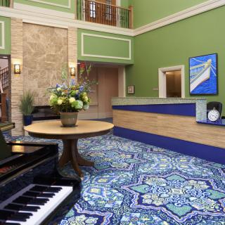 A stylish lobby featuring a piano, reception desk, and decorative elements.