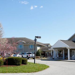 A residential building with a parking lot and landscaped surroundings under a clear blue sky.