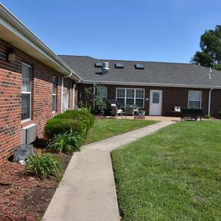 A well-maintained residential building with a brick exterior and a neatly trimmed yard, featuring a winding concrete pathway.