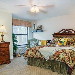 A traditional bedroom with a wooden bed, patterned bedding, and a ceiling fan.