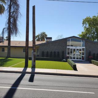 A modern building with a well-maintained exterior and lush green landscaping under a clear blue sky.