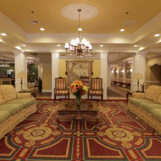 A luxurious hotel lobby with elegant seating, a chandelier, and ornate carpeting.