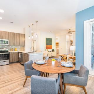 A modern open-concept dining and kitchen area with stylish furnishings and wood flooring.