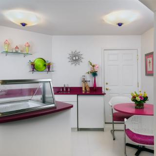 A charming retro-style ice cream shop with pink and white decor, featuring a counter and cozy seating area.