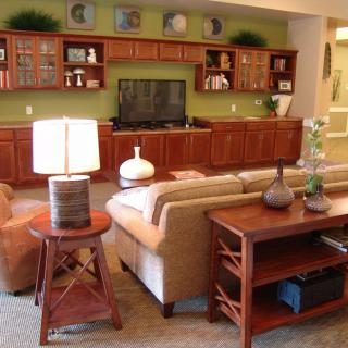 A cozy living room with a sofa, lamp, and television surrounded by wooden shelves and cabinets.