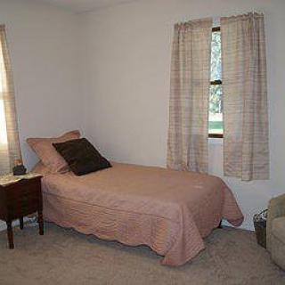 A minimalist bedroom with a single bed and two curtained windows.