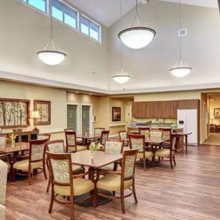 A spacious dining area with neatly arranged tables and chairs, featuring elegant lighting and a warm interior design.