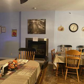 A cozy dining room with tables, chairs, a fireplace, and decorative elements on the walls.