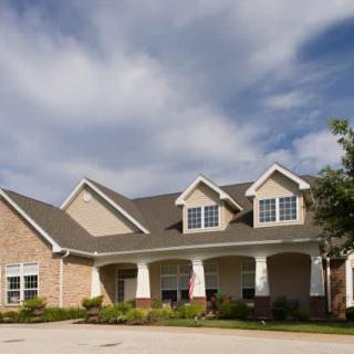 A modern suburban house with brick facade and landscaped front yard under a cloudy sky.