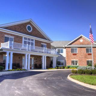 A brick building with a driveway and an American flag on a sunny day.