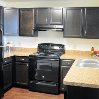 Modern kitchen with dark cabinets and black appliances.
