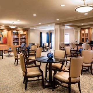 A spacious lounge area with multiple tables and chairs, well-lit with warm lighting.