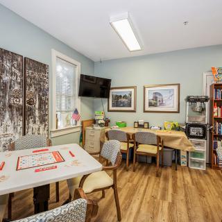A cozy office meeting room with tables, chairs, and artwork on the walls.