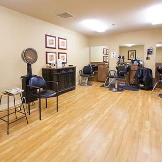 A spacious hair salon interior with chairs and mirrors, featuring wooden flooring.