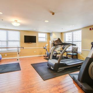 A well-lit gym with treadmills and exercise equipment on a hardwood floor.