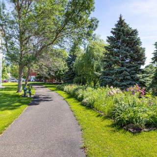 A serene walking path lined with trees and colorful flowers in a vibrant park.