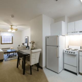 A compact apartment interior featuring a kitchen with appliances and an adjoining dining and living area.